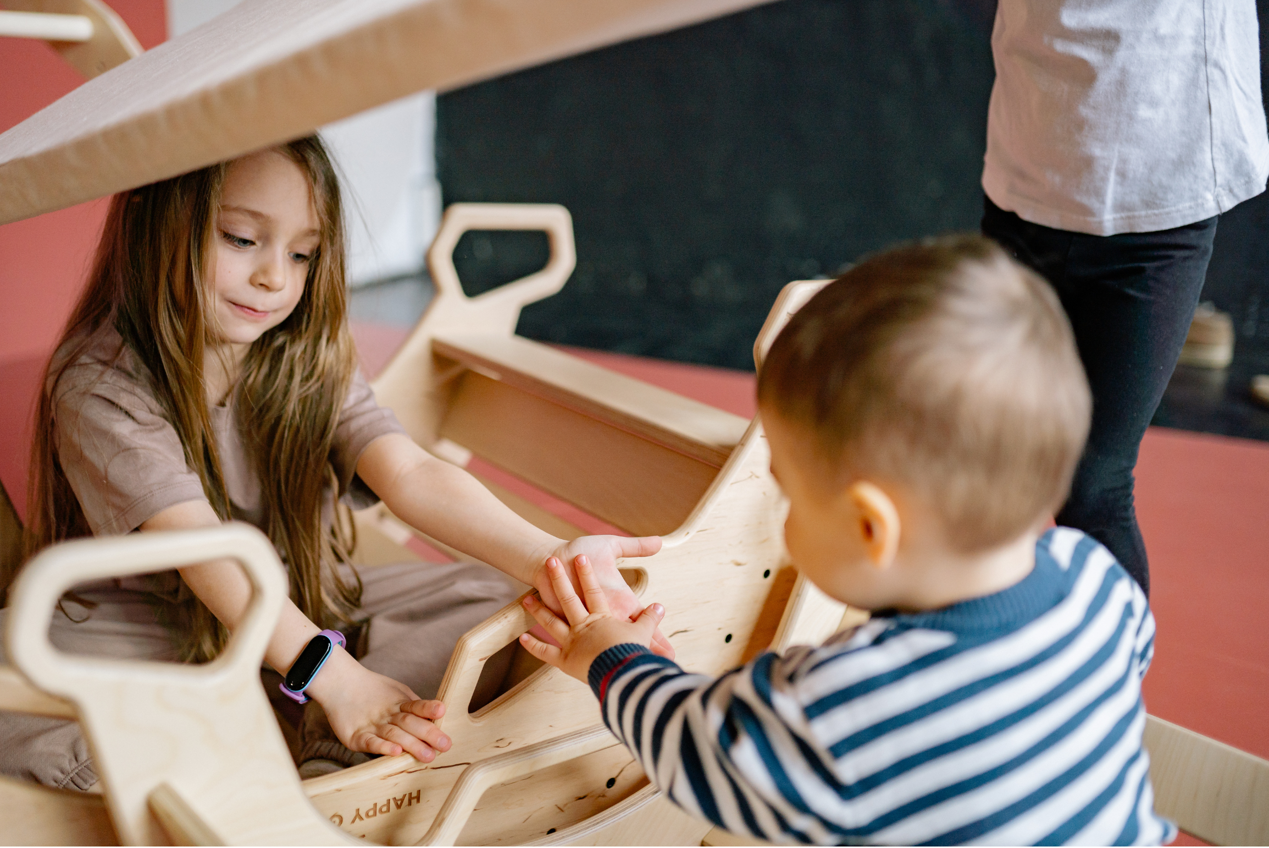 Mom holding toddler while-baby-is-in-crib-showing-divided-attention