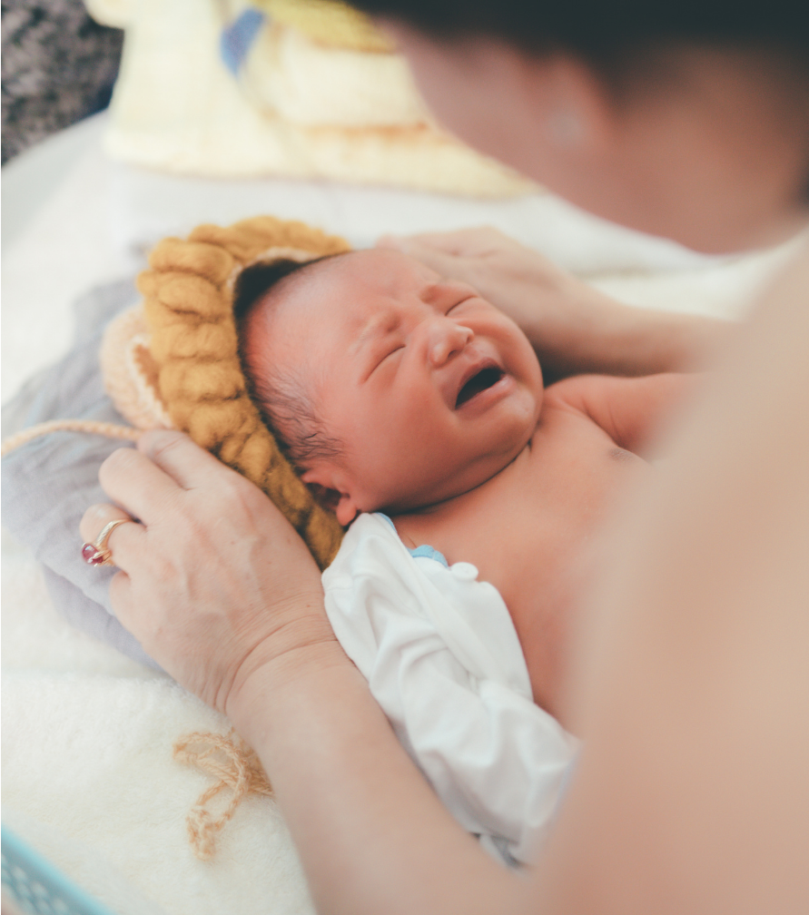 Calm nursery setup with dim lights, white noise machine, swaddled baby in crib.